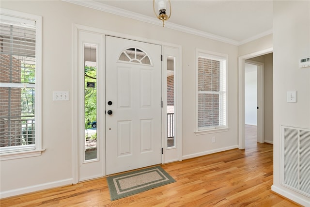 foyer featuring a wealth of natural light, ornamental molding, and light wood-type flooring