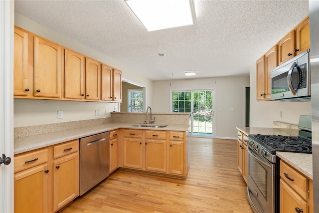 kitchen featuring sink, light wood-type flooring, kitchen peninsula, stainless steel appliances, and light brown cabinets