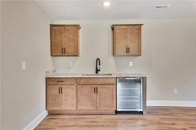 kitchen featuring wine cooler, light wood-type flooring, and sink