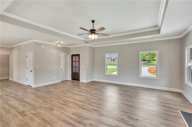 spare room with a raised ceiling, light hardwood / wood-style floors, crown molding, and ceiling fan