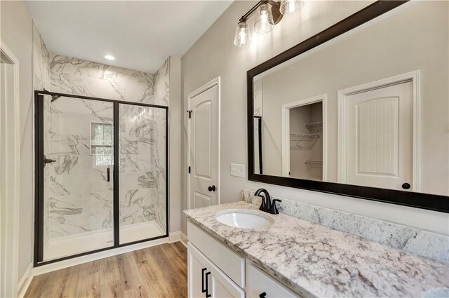 bathroom with wood-type flooring, vanity, and an enclosed shower