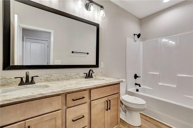 full bathroom with wood-type flooring, vanity, toilet, and washtub / shower combination