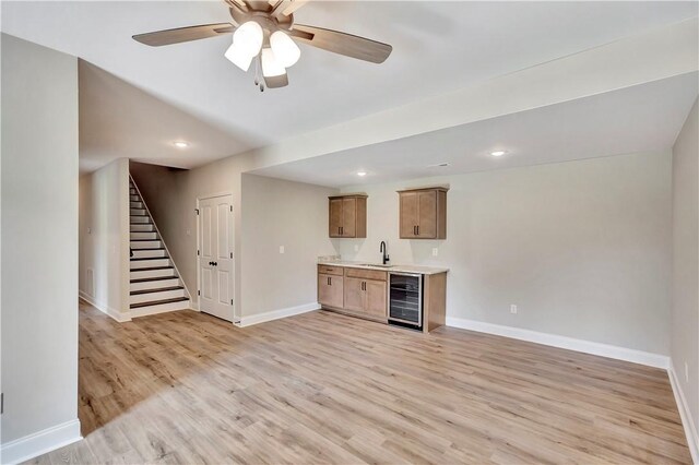 bar featuring light hardwood / wood-style floors, sink, ceiling fan, and beverage cooler