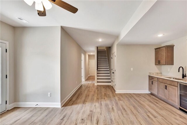 kitchen with ceiling fan, light wood-type flooring, light stone counters, and sink