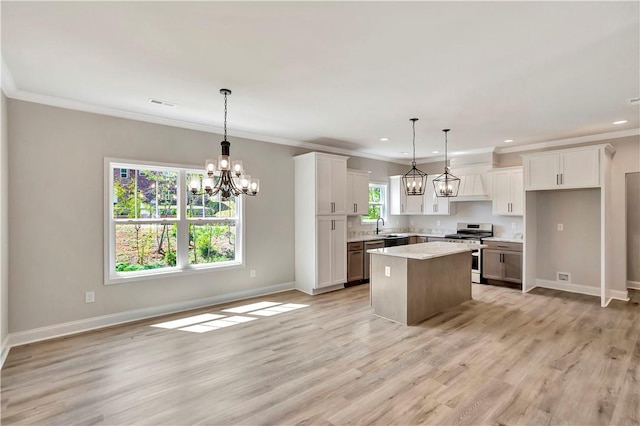 kitchen featuring stainless steel range with gas stovetop, white cabinets, pendant lighting, and a kitchen island