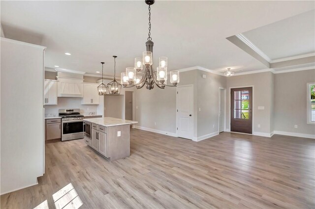 kitchen featuring white cabinets, hanging light fixtures, stainless steel appliances, a center island, and light wood-type flooring