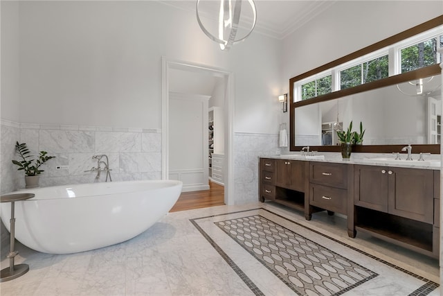 bathroom featuring tile walls, vanity, crown molding, and a tub