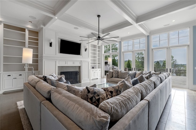 tiled living room featuring ceiling fan, beam ceiling, coffered ceiling, and built in shelves