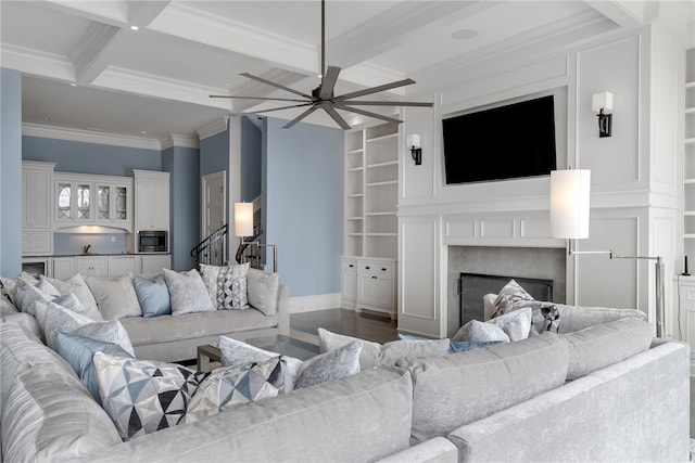 living room with beam ceiling, crown molding, built in shelves, and ceiling fan