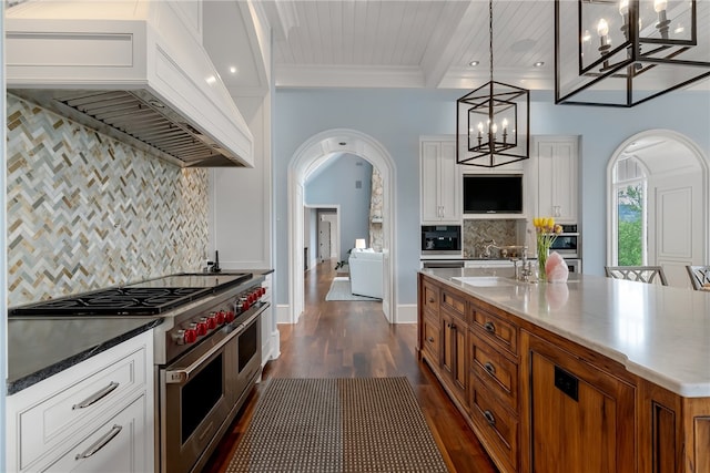 kitchen featuring dark wood-type flooring, stainless steel appliances, decorative light fixtures, custom exhaust hood, and white cabinets