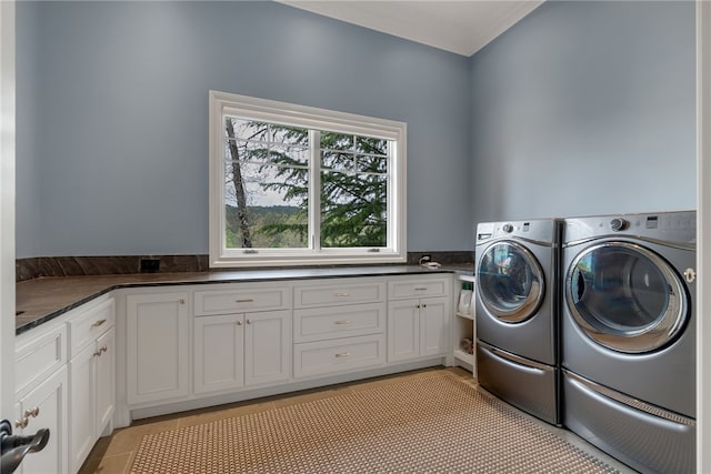 clothes washing area with light tile patterned floors, washing machine and dryer, and cabinets