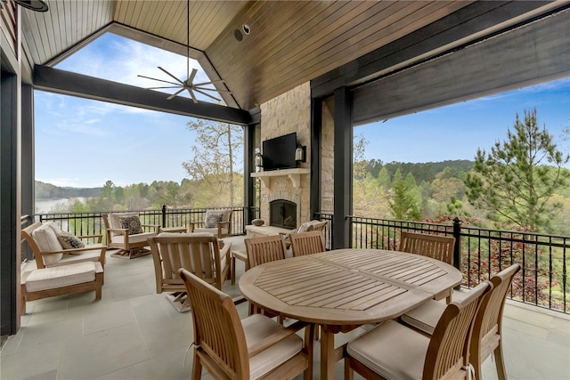 sunroom / solarium featuring lofted ceiling, an outdoor stone fireplace, wood ceiling, and a wealth of natural light