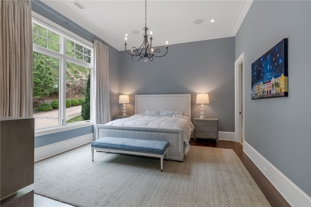 bedroom with ornamental molding, hardwood / wood-style floors, and an inviting chandelier