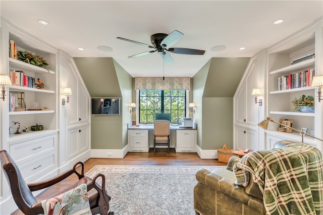 home office featuring ceiling fan, lofted ceiling, built in features, built in desk, and light wood-type flooring