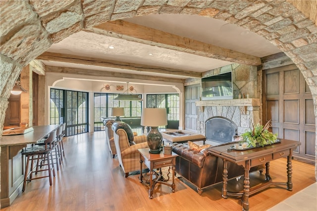 living room featuring beamed ceiling, a fireplace, and hardwood / wood-style flooring