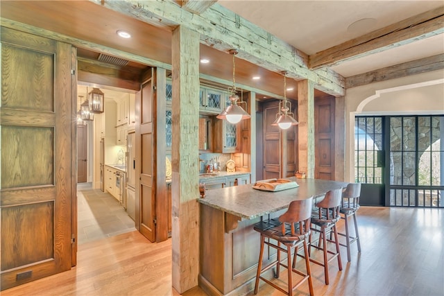 bar featuring pendant lighting, light stone counters, light hardwood / wood-style floors, and beamed ceiling