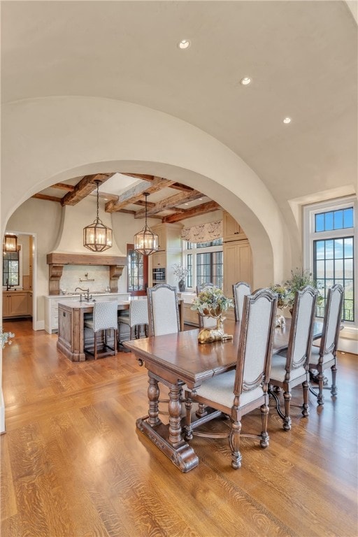 dining room featuring a notable chandelier, vaulted ceiling with beams, and light hardwood / wood-style floors