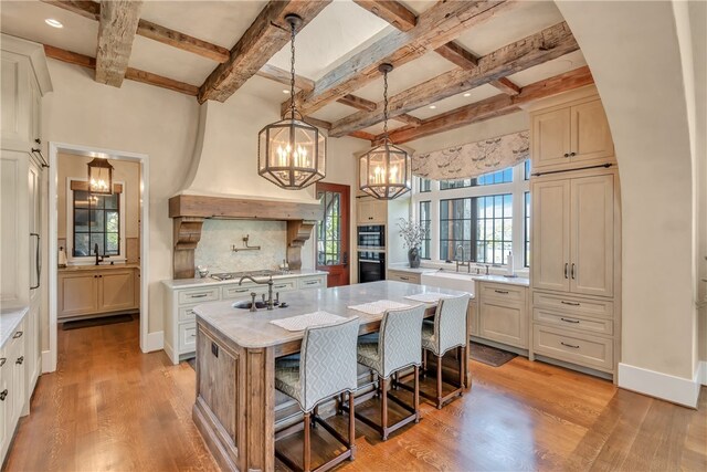 kitchen with pendant lighting, light hardwood / wood-style floors, a center island with sink, and a breakfast bar area