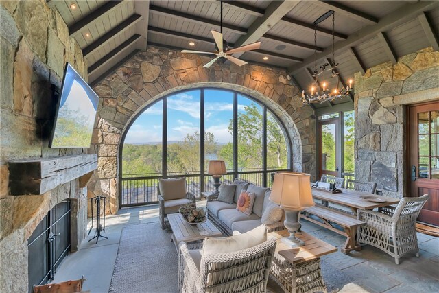 sunroom featuring wood ceiling, vaulted ceiling with beams, ceiling fan with notable chandelier, and a stone fireplace