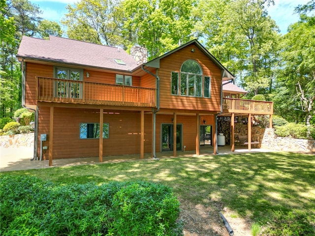 back of property with a lawn, a wooden deck, and a patio area