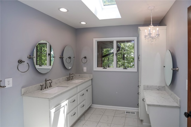 bathroom with an inviting chandelier, a skylight, and vanity