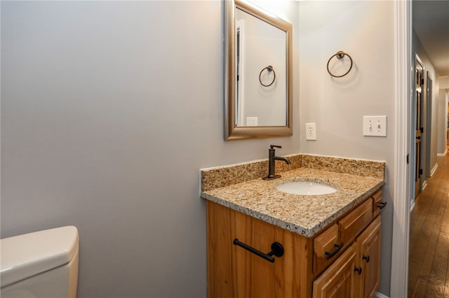 bathroom with vanity, toilet, and hardwood / wood-style flooring