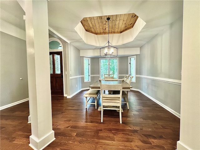 dining room featuring an inviting chandelier, a tray ceiling, and dark hardwood / wood-style flooring