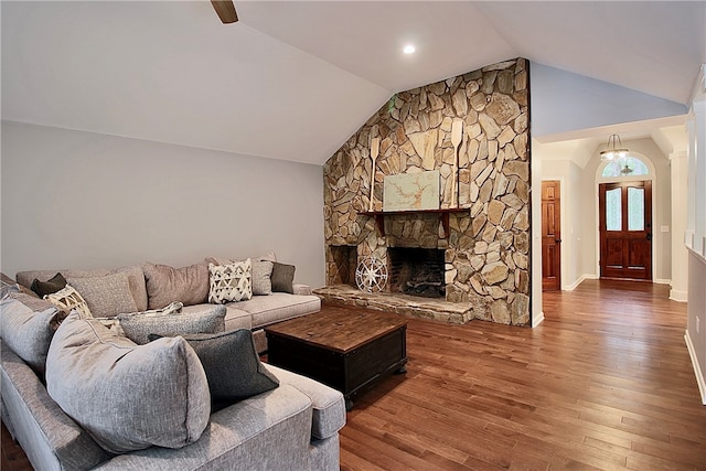 living room with a stone fireplace, lofted ceiling, and dark wood-type flooring