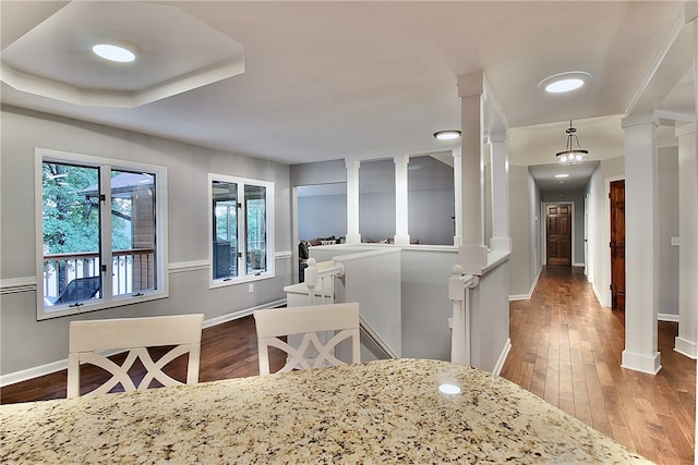 dining area with a tray ceiling, decorative columns, and hardwood / wood-style floors