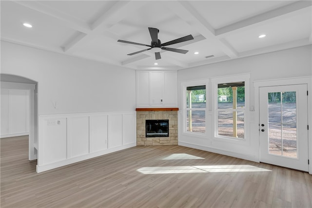 unfurnished living room featuring ceiling fan, beamed ceiling, coffered ceiling, a fireplace, and light hardwood / wood-style floors