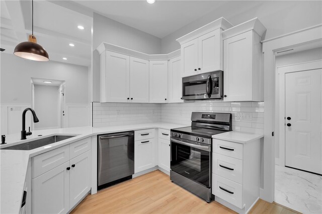 kitchen featuring sink, white cabinetry, decorative backsplash, stainless steel appliances, and decorative light fixtures