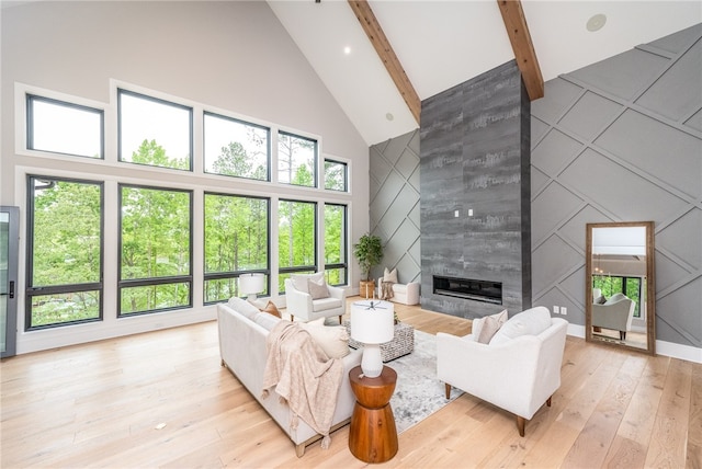 living room with high vaulted ceiling, light hardwood / wood-style floors, beamed ceiling, and a healthy amount of sunlight