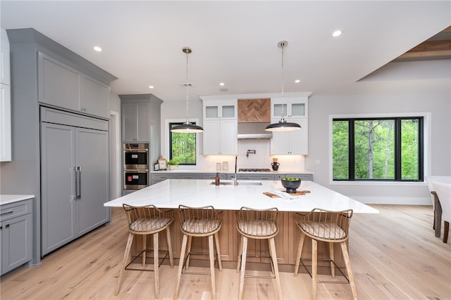 kitchen featuring paneled built in refrigerator, gray cabinetry, a large island, and light hardwood / wood-style flooring