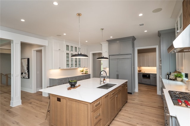 kitchen featuring light hardwood / wood-style floors, a center island with sink, sink, and gray cabinetry