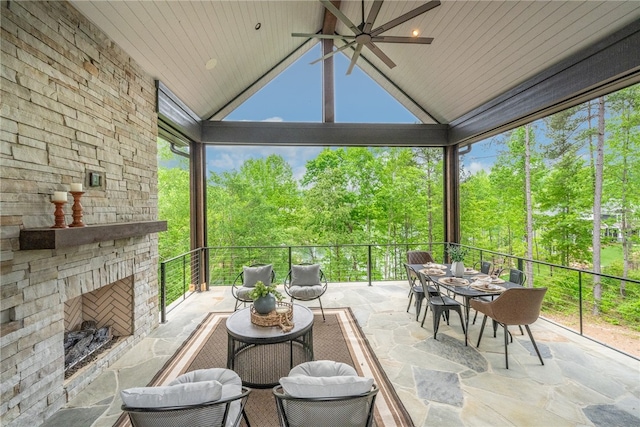 sunroom featuring wooden ceiling, vaulted ceiling, ceiling fan, and an outdoor stone fireplace