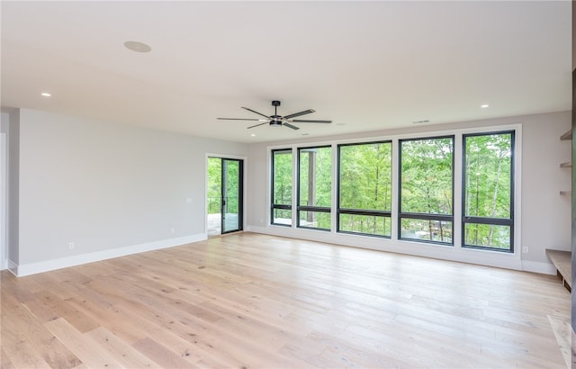 empty room with ceiling fan and light hardwood / wood-style flooring