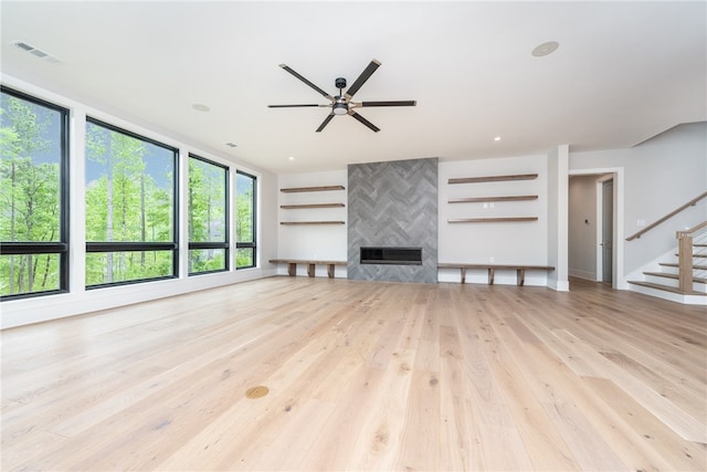 unfurnished living room featuring light hardwood / wood-style flooring, a large fireplace, and ceiling fan