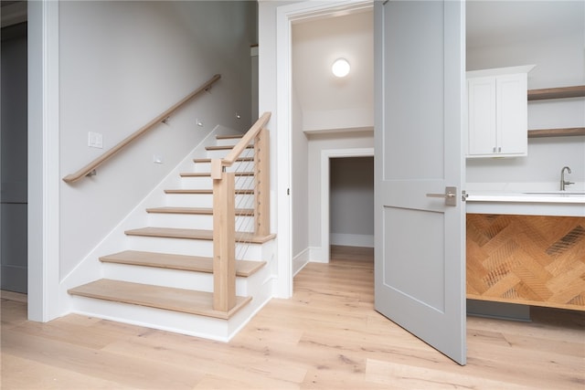 stairs featuring sink and hardwood / wood-style floors