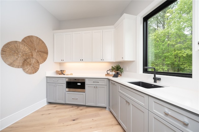 kitchen featuring light hardwood / wood-style floors, sink, oven, and gray cabinets