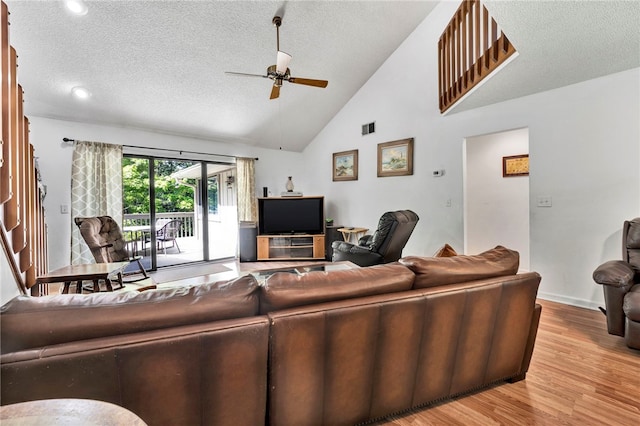 living room with a textured ceiling, light hardwood / wood-style floors, high vaulted ceiling, and ceiling fan