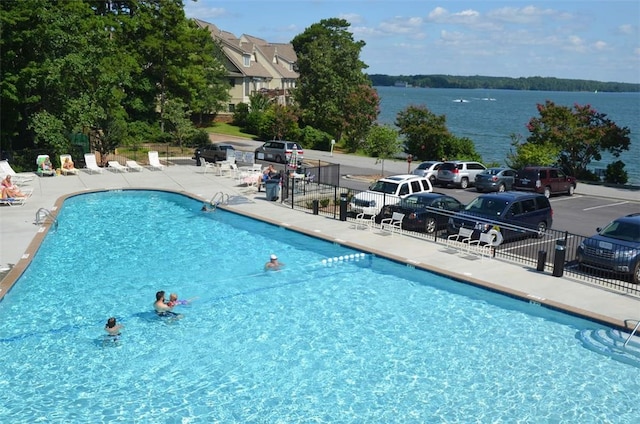 view of swimming pool featuring a water view and a patio