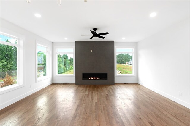 unfurnished living room featuring wood-type flooring, a fireplace, and a healthy amount of sunlight