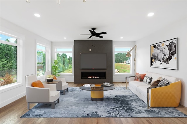 living room featuring a large fireplace, ceiling fan, plenty of natural light, and hardwood / wood-style floors