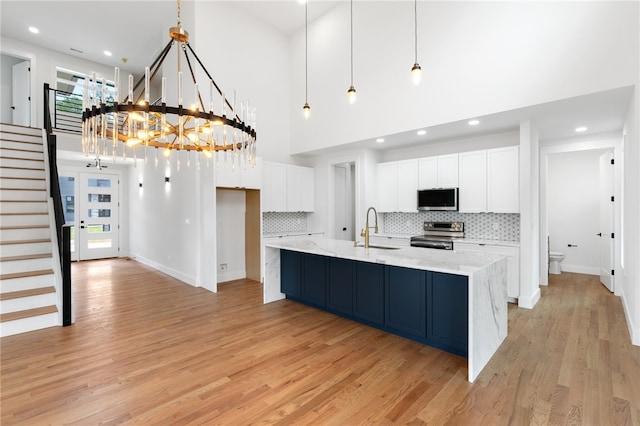 kitchen with light wood-type flooring, hanging light fixtures, sink, and stainless steel appliances