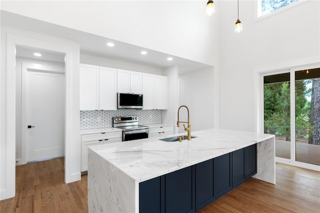 kitchen with appliances with stainless steel finishes, sink, white cabinetry, and a healthy amount of sunlight