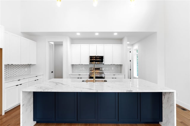 kitchen featuring white cabinetry, appliances with stainless steel finishes, light stone counters, and a spacious island