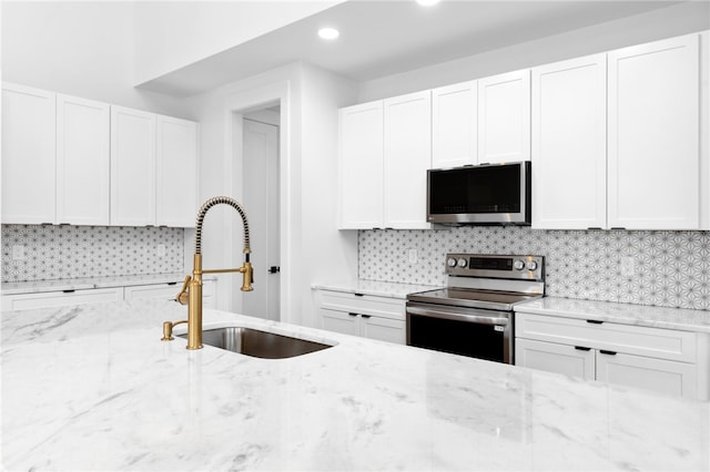 kitchen with appliances with stainless steel finishes, white cabinetry, and sink