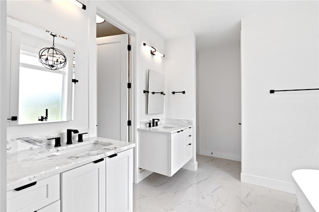 bathroom with a notable chandelier, vanity, and a bathtub