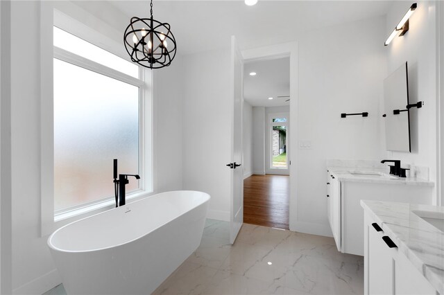 bathroom with vanity, hardwood / wood-style floors, a chandelier, and a tub