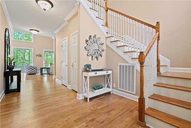 staircase with wood-type flooring and crown molding